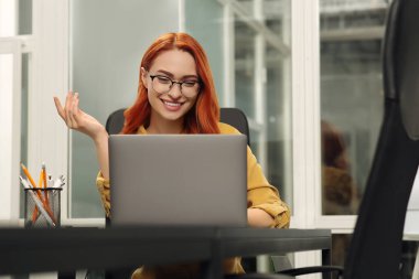 Ofisteki bilgisayarında online toplantı yapan mutlu bir kadın.