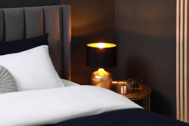 Yatak, yastıklar, lamba ve odadaki komodinin üzerinde farklı dekorlar. Şık iç mekan