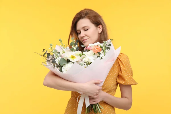 黄色の背景に花の花束を持つ美しい女性 — ストック写真