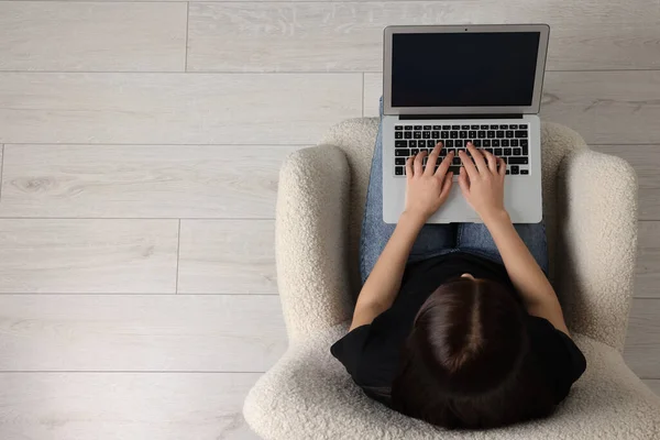 stock image Woman working with laptop in armchair, top view. Space for text