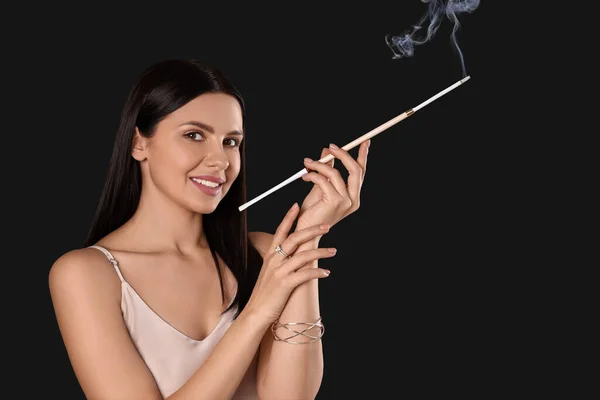 stock image Woman using long cigarette holder for smoking on black background, space for text