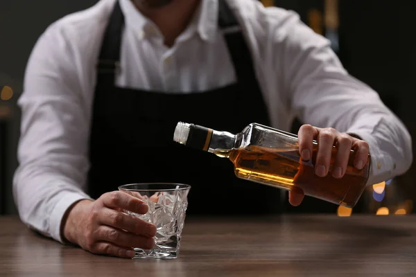 バーカウンター内のガラスに瓶からウイスキーを注ぐバーテンダー クローズアップ — ストック写真