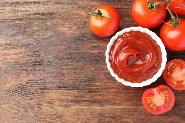 stock image Bowl of tasty ketchup and tomatoes on wooden table, flat lay. Space for text