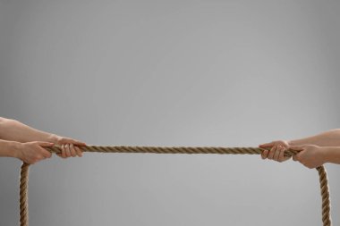 Tartışma konsepti. Açık gri arka planda ip çeken adamlar, yakın plan. Metin için boşluk