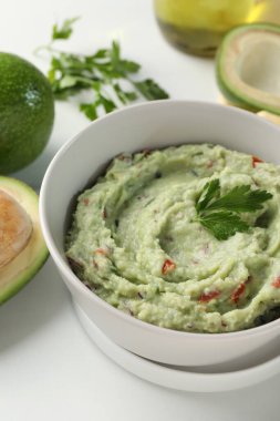 Lezzetli guacamole ve malzemeler beyaz masada.