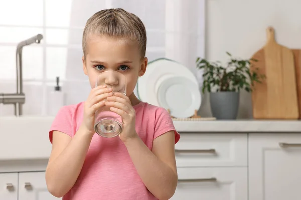 可爱的小女孩在厨房里用杯子喝水 — 图库照片