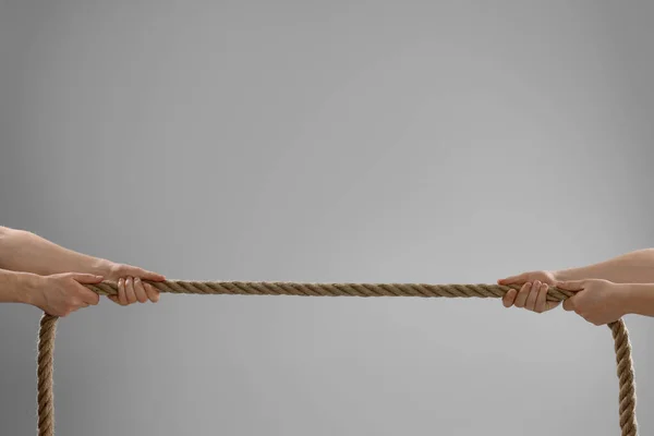 stock image Dispute concept. Men pulling rope on light grey background, closeup. Space for text