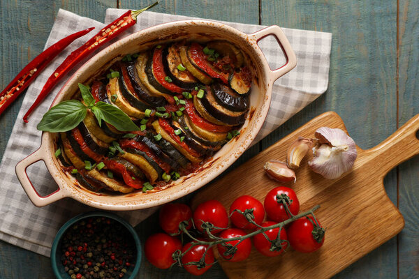 Delicious ratatouille and ingredients on wooden table, flat lay