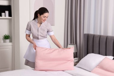 Genç hizmetçi otel odasında yatak yapma