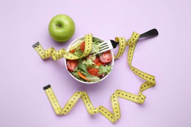 Taze sebze salatası, çatal, elma ve menekşe arka planında mezura, düz yatak. Sağlıklı diyet kavramı