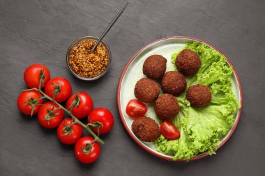 Lezzetli falafel topları, domatesler, marul ve tahıllı hardal koyu gri desenli masa, düz yatak. Vegan et ürünleri