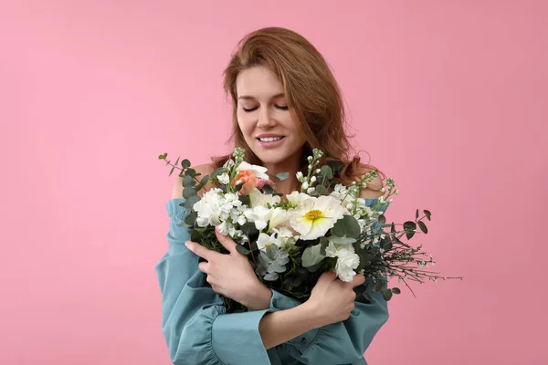 ピンクの背景に花の花束を持つ美しい女性 — ストック写真
