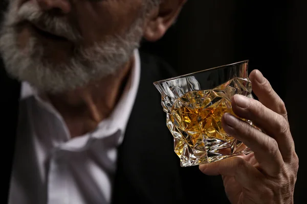 男人拿着威士忌 在黑暗的背景上放冰块 — 图库照片