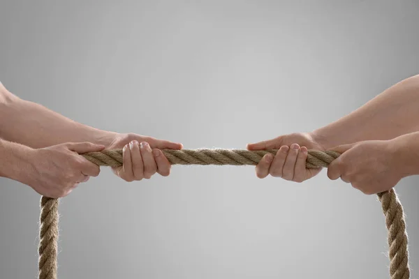 stock image Dispute concept. Men pulling rope on light grey background, closeup