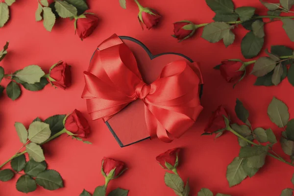 Pudełko Kształcie Serca Łukiem Pięknymi Różami Czerwonym Tle Płaskie Leżaki — Zdjęcie stockowe