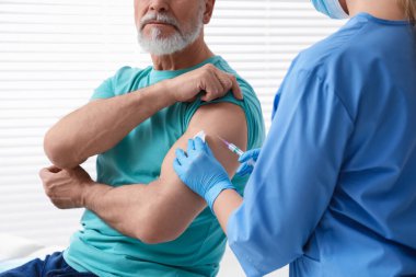 Doktor klinikteki hastaya hepatit aşısı veriyor.