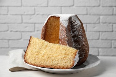 Delicious Pandoro cake decorated with powdered sugar on white table. Traditional Italian pastry