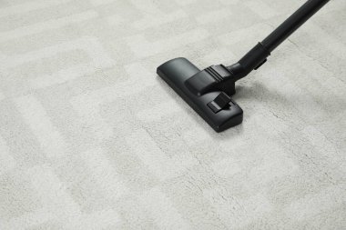 Modern elektrikli süpürgeyle beyaz halı süpürüyorsun. Metin için boşluk