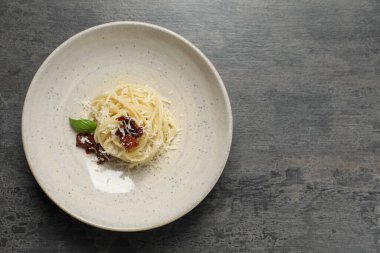 Lezzetli spagetti, güneşte kurutulmuş domates ve peynirli gri masa, üst manzara ve yazı için yer. Makarna yemeğinin enfes sunumu