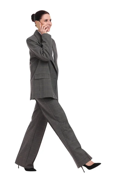 白い背景を背景に歩きながらスマホで話す美しい幸せビジネスウーマン — ストック写真