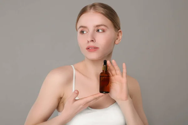Mooie Jonge Vrouw Met Fles Etherische Olie Lichtgrijze Achtergrond — Stockfoto