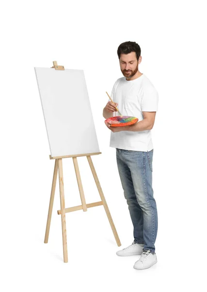 白を背景に筆とアーティストのパレット絵画を持つ男 キャンバスを保持するためにイーゼルを使用 — ストック写真