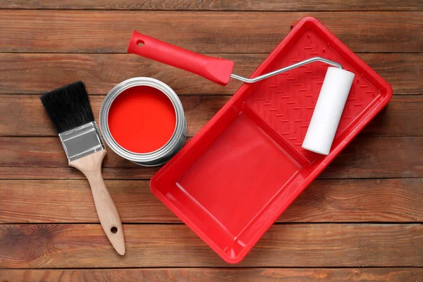 stock image Can of red paint, brush, roller and tray on wooden table, flat lay