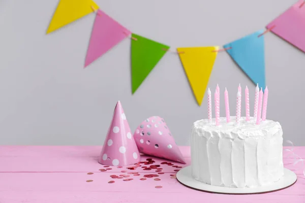 有蜡烛和派对帽的美味蛋糕放在粉红色的木制桌子上 案文的篇幅 — 图库照片