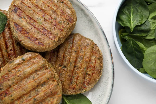 Stock image Tasty grilled vegan cutlets and spinach on white table, top view