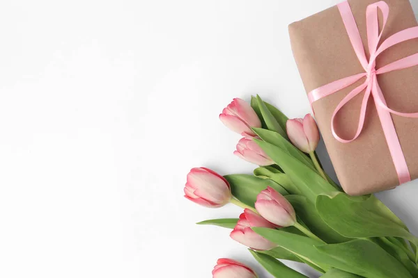 stock image Beautiful gift box with bow and pink tulips on white background, flat lay. Space for text