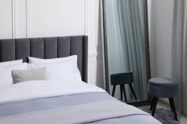 Sıcak yatak, ayna ve puf şık yatak odasında.