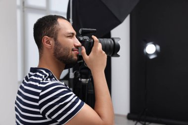 Modern fotoğraf stüdyosunda fotoğraf çeken genç profesyonel fotoğrafçı.