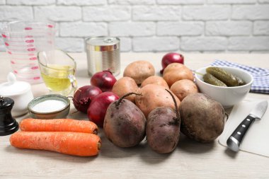 Beyaz ahşap masada bir sürü taze sebze ve diğer malzemeler var. Sirkeli salata pişiriyorum.