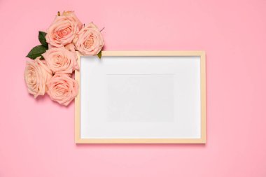 Boş fotoğraf çerçevesi ve pembe arka planda güzel güller. Tasarım için model