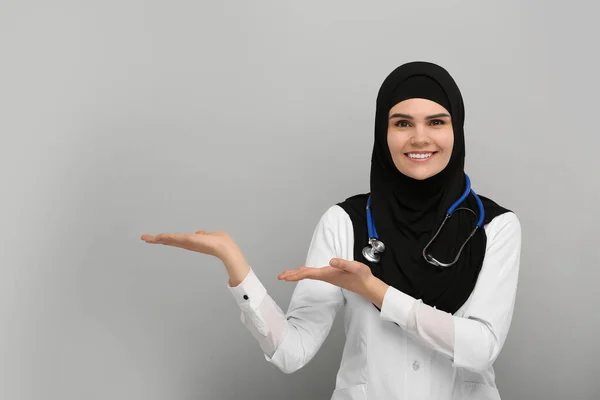 Mujer Musulmana Hiyab Uniforme Médico Señalando Algo Sobre Fondo Gris — Foto de Stock