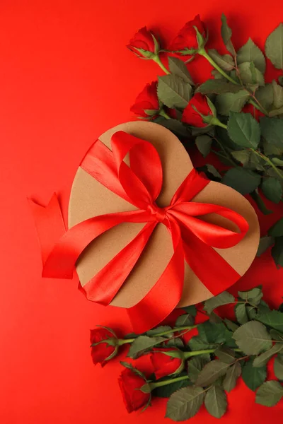 Herzförmige Geschenkschachtel Mit Schleife Und Schönen Rosen Auf Rotem Hintergrund — Stockfoto