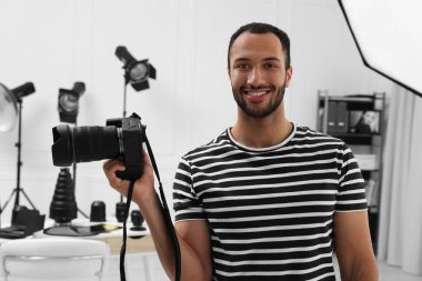 Modern fotoğraf stüdyosunda kamerası olan genç profesyonel fotoğrafçı.