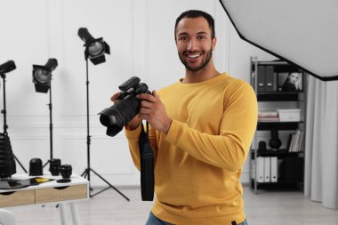 Modern fotoğraf stüdyosunda kamerası olan genç profesyonel fotoğrafçı.