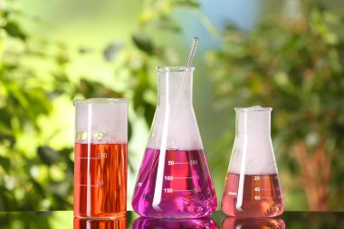 Laboratory glassware with colorful liquids on glass table outdoors. Chemical reaction