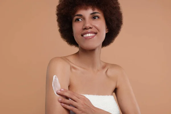 Mooie Jonge Vrouw Aanbrengen Lichaam Crème Arm Beige Achtergrond — Stockfoto
