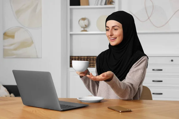 Muslimische Frau Mit Tasse Kaffee Videochat Auf Laptop Holztisch Zimmer — Stockfoto