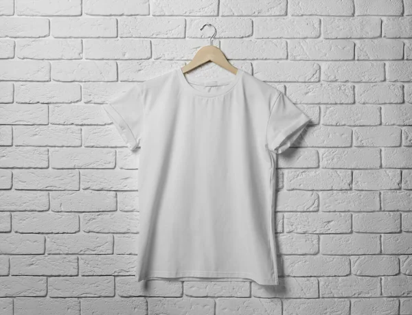 白いレンガの壁にスタイリッシュなTシャツでハンガー — ストック写真