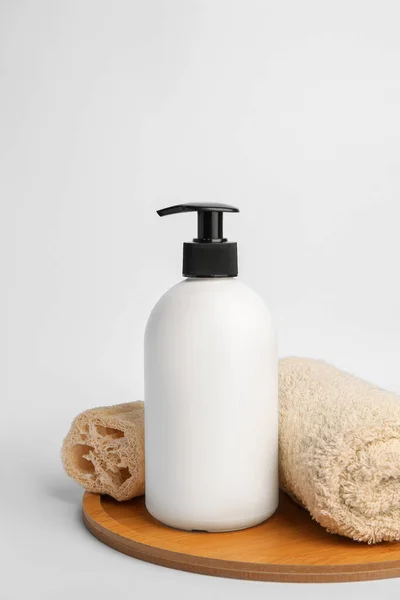 stock image Bottle with cosmetic product, rolled towel and loofah sponge on white background