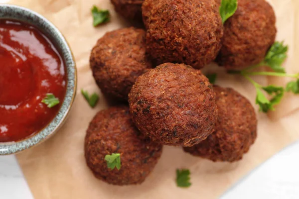 stock image Vegan meat products. Delicious falafel balls, parsley and sauce on table, flat lay