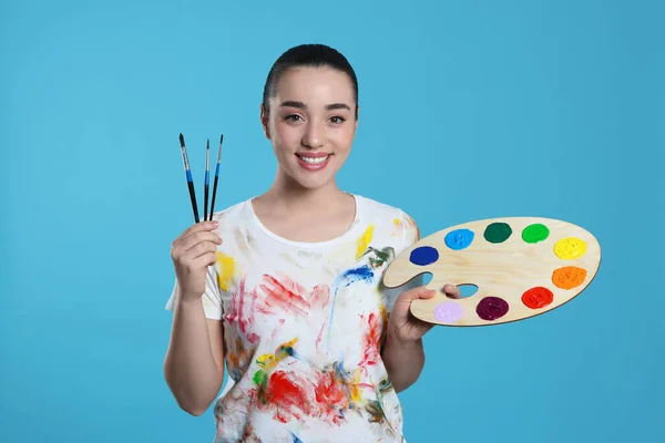拥有浅蓝色背景的绘画工具的女人 年轻的艺术家 — 图库照片