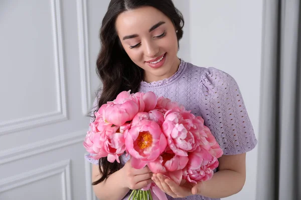 ピンクの牡丹の花束と美しい若い女性屋内 — ストック写真