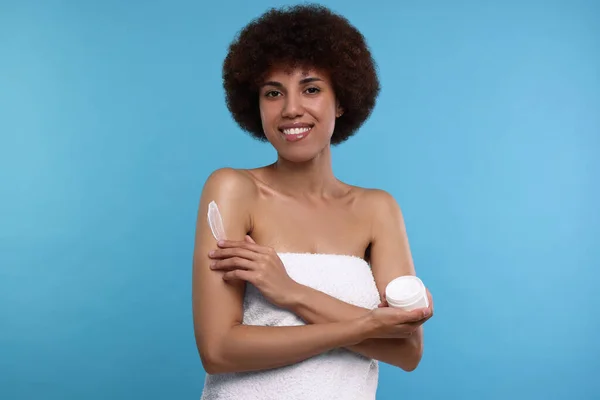 Mooie Jonge Vrouw Aanbrengen Lichaam Crème Arm Licht Blauwe Achtergrond — Stockfoto