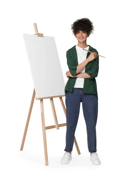 年轻女子拿着画笔靠近画架 画布衬着白色背景 — 图库照片