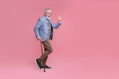 Pembe arka planda bastonlu son sınıf öğrencisi.