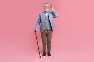 Pembe arka planda bastonlu son sınıf öğrencisi.